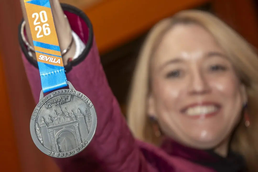  La delegada de Deportes muestra la medalla de la Media Marat&oacute;n de Sevilla, inspirada en el Arco de la Macarena en esta edici&oacute;n | AYTO DE SEVILLA 