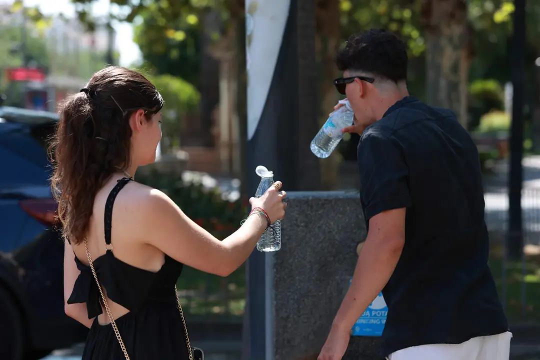  Una pareja bebe agua en una fuente de Sevilla capital. | EP 