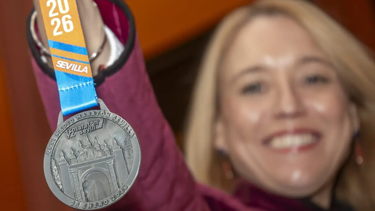  La delegada de Deportes muestra la medalla de la Media Marat&oacute;n de Sevilla, inspirada en el Arco de la Macarena en esta edici&oacute;n | AYTO DE SEVILLA 