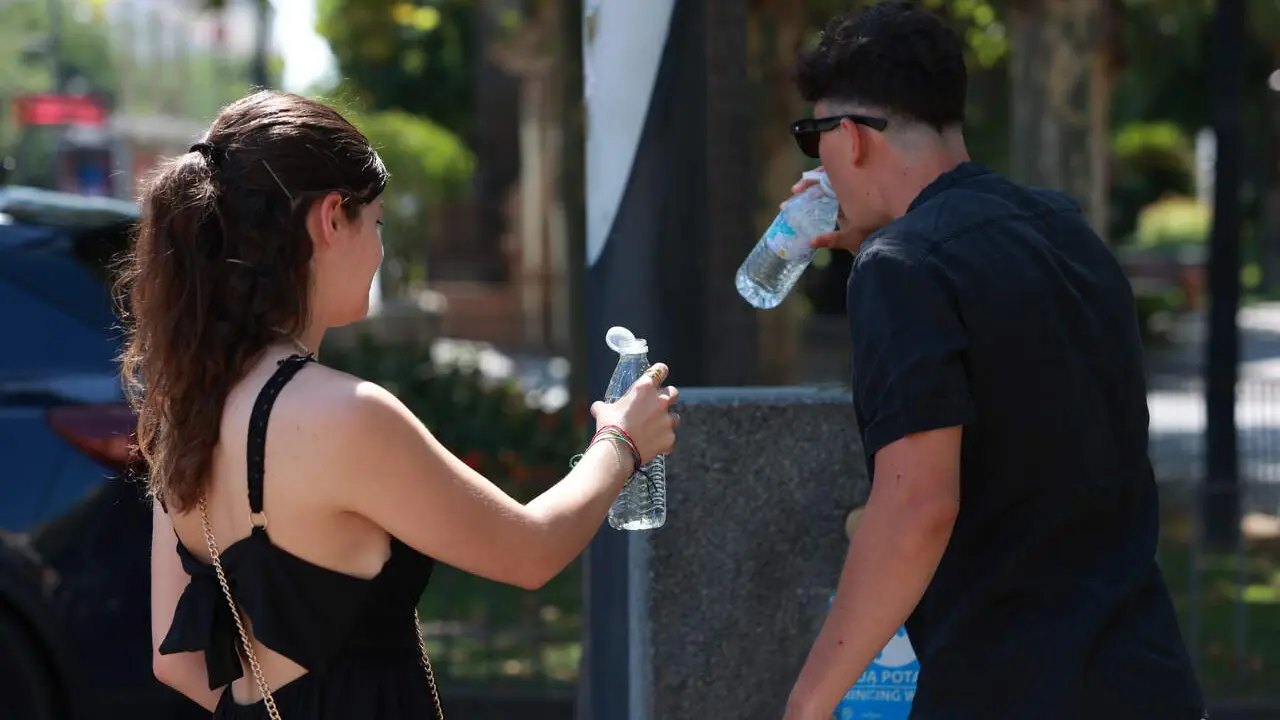  Una pareja bebe agua en una fuente de Sevilla capital. | EP 